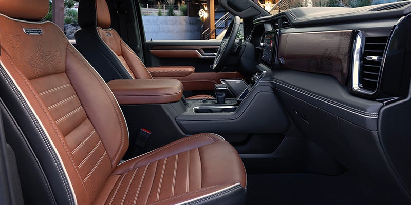 Interior view of a car showing front seats with brown leather upholstery and stitching.