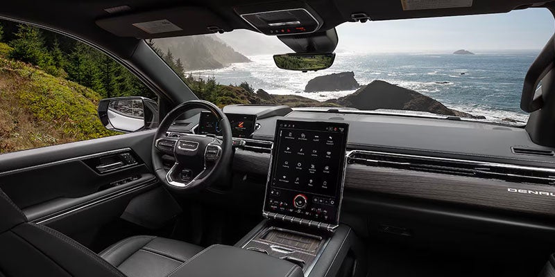 
GMC vehicle interior with a large vertical touchscreen overlooking a rugged coastline.